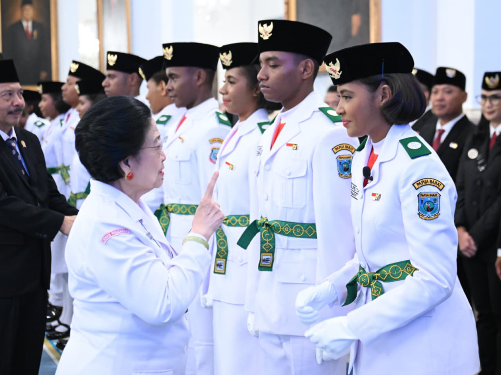 Anggota Paskibraka 2025 asal Papua Barat Ritha Lovely CF Ayomi mencium Bendera Merah-Putih dalam upacara pengukuhan Paskibraka Tingkat Pusat 2025 di Istana Negara, Jakarta, Sabtu (16/8/2025).  (Beritanasional.com/ Biro Pers)