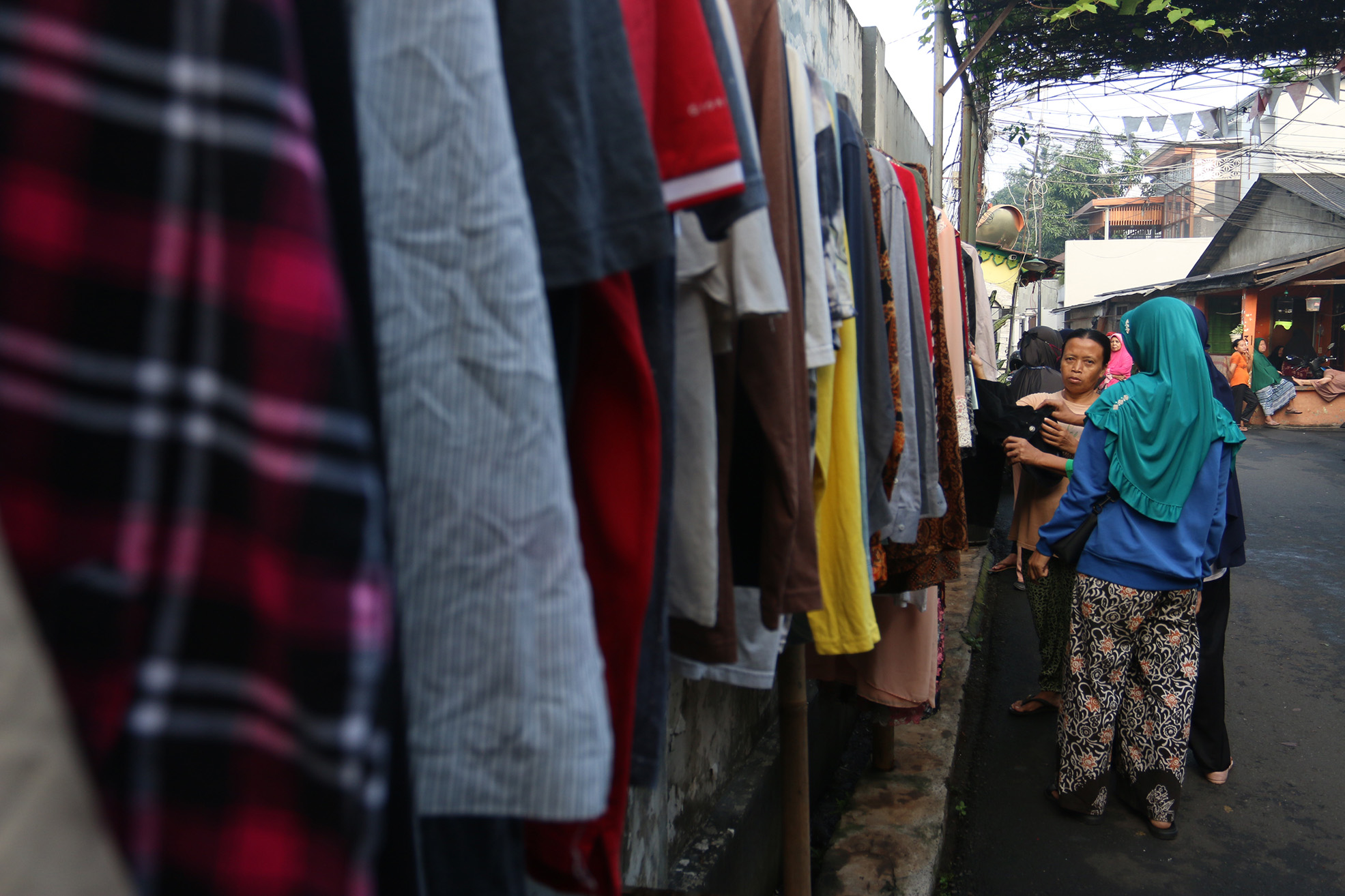 Warga memilih sayur dan pakaian bekas saat bazzar sayuran, bahan makanan dan pakaian layak pakai gratis di Jalan Jati Padang VI, Pasar Minggu, Jakarta, Jumat (29/03/2024).(Indonesiaglobe/Oke Atmaja)