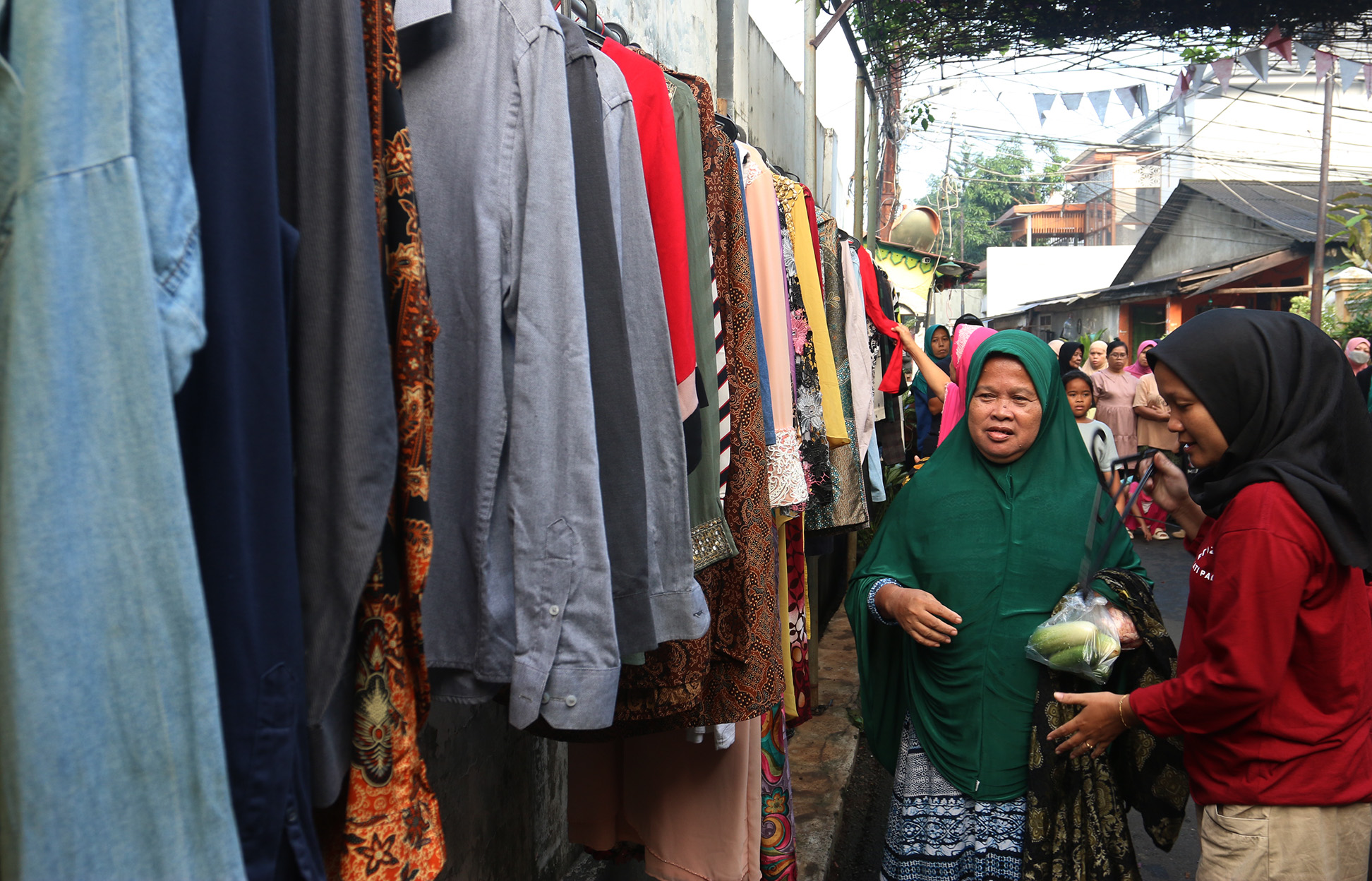 Warga memilih sayur dan pakaian bekas saat bazzar sayuran, bahan makanan dan pakaian layak pakai gratis di Jalan Jati Padang VI, Pasar Minggu, Jakarta, Jumat (29/03/2024).(Indonesiaglobe/Oke Atmaja)