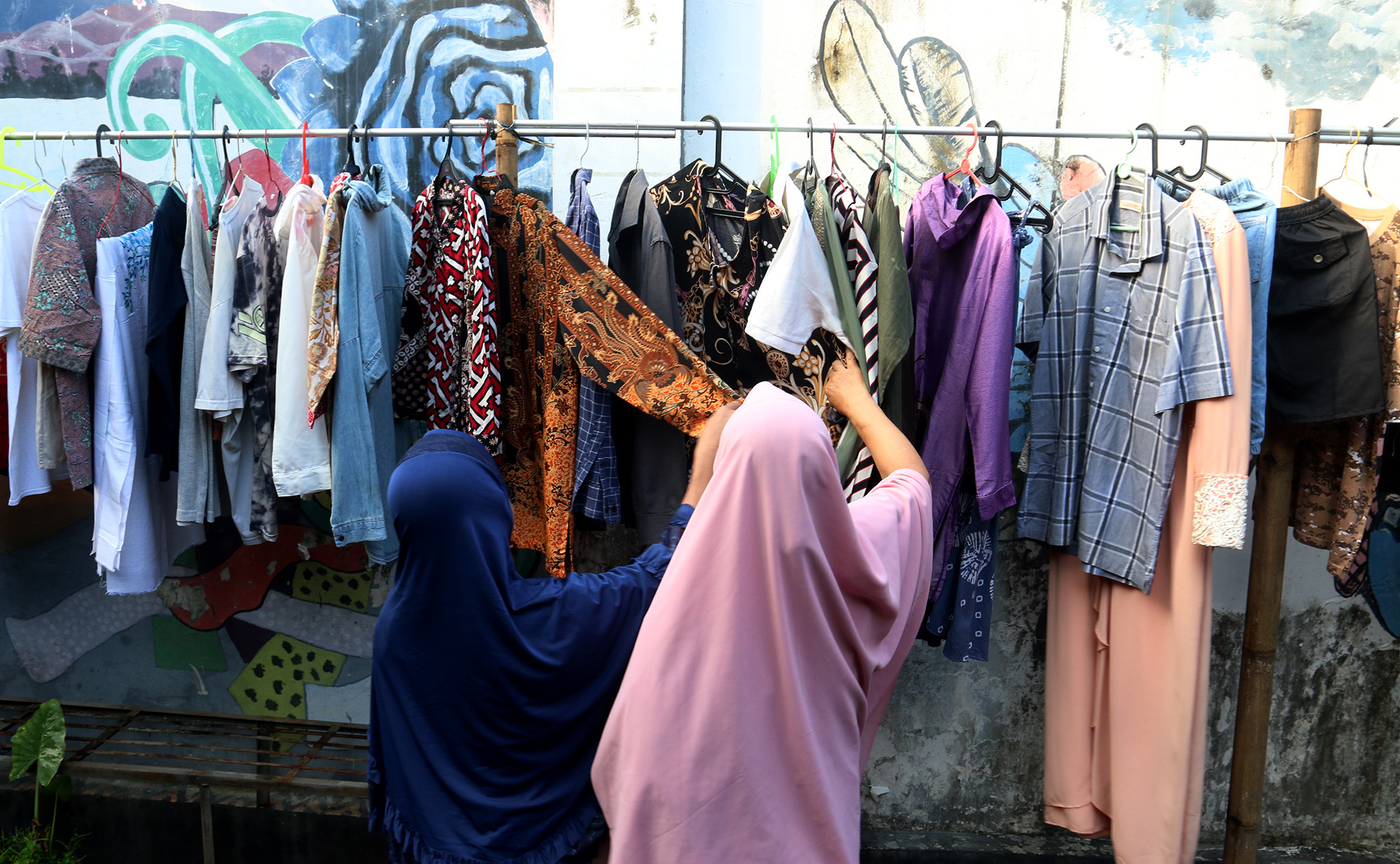 Warga memilih sayur dan pakaian bekas saat bazzar sayuran, bahan makanan dan pakaian layak pakai gratis di Jalan Jati Padang VI, Pasar Minggu, Jakarta, Jumat (29/03/2024).(Indonesiaglobe/Oke Atmaja)