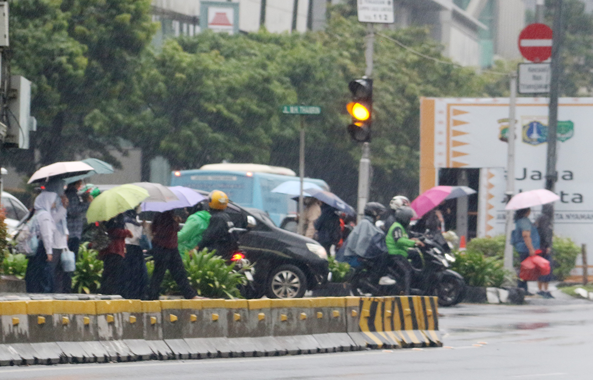 Cuaca hari ini - Pekerja melintas di jalan MH. Thamrin,Jakarta, Senin (12/1/2025). (Beritanasional.com/Oke Atmaja)