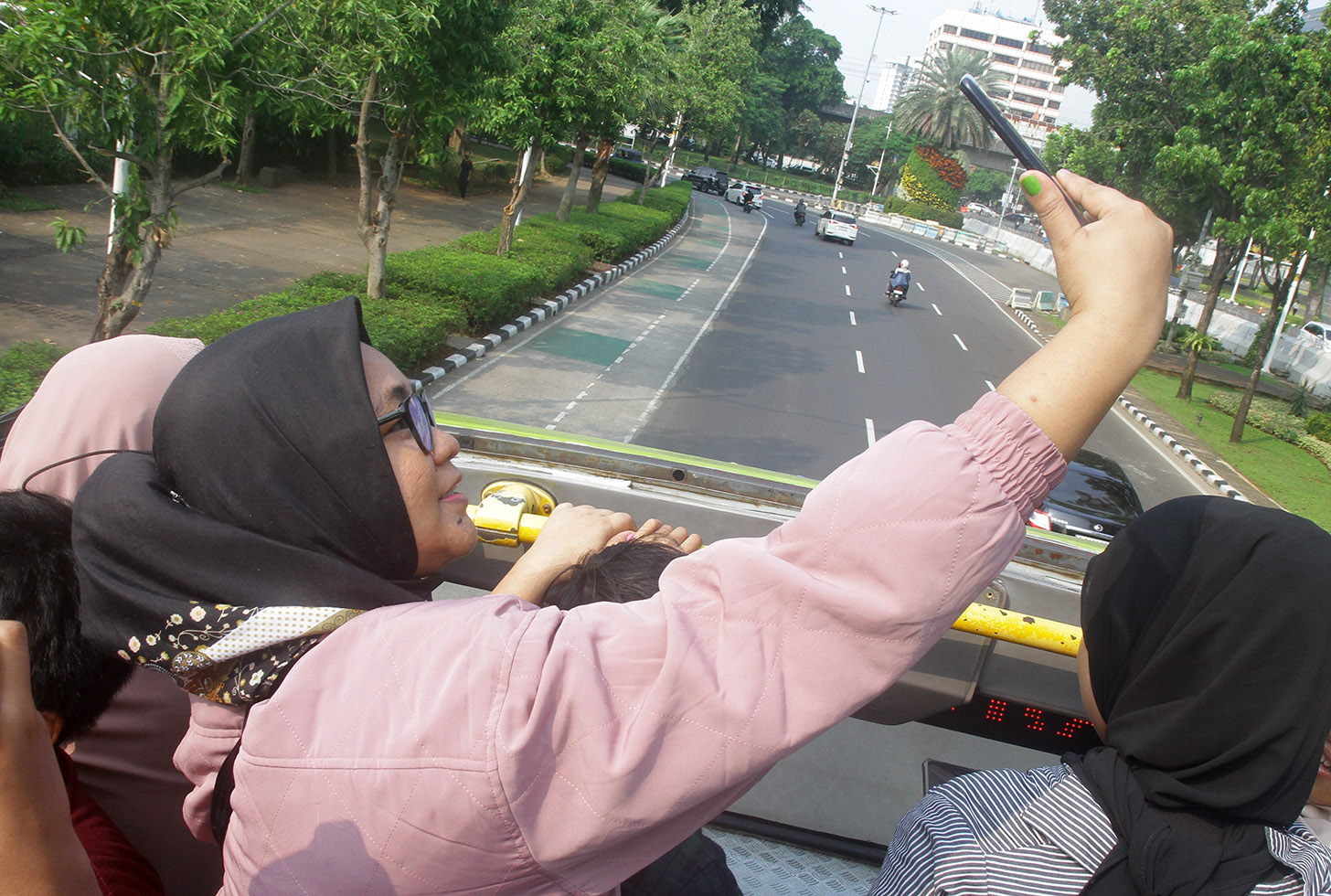 Sejumlah penumpang menaiki bus tingkat pariwisata gratis di kawasan Monas, Jakarta,minggu (7/7/2024).(BeritaNasional.com/Oke Atmaja)