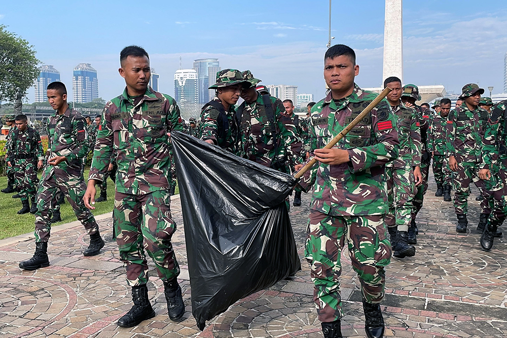 Prajurit Yonif 330 Tri Dharma membersihkan sampah di kawasan lingkungan lapangan silang Monas. (BeritaNasional/HO TNI/Elvis Sendouw)