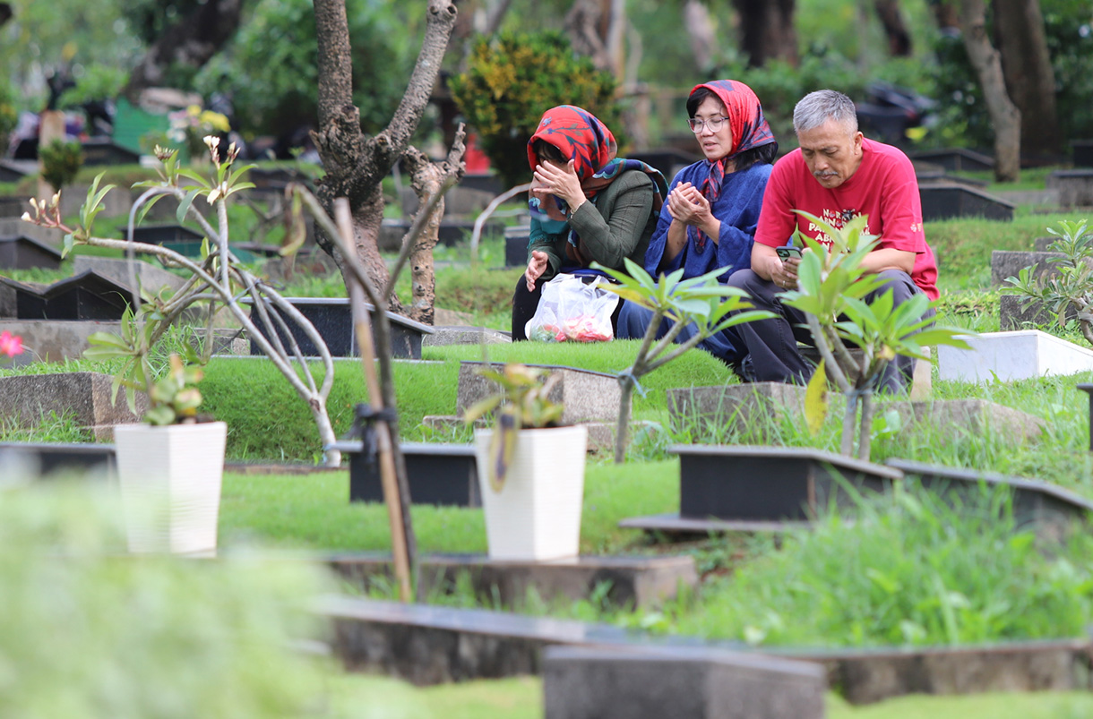 Sejumlah warga berdoa menaburkan bunga di makam keluarganya di tempat pemakaman umum Karet Bivak,Jakarta, Jumat(28/2/2025). (Beritanasional.com/Oke Atmaja)