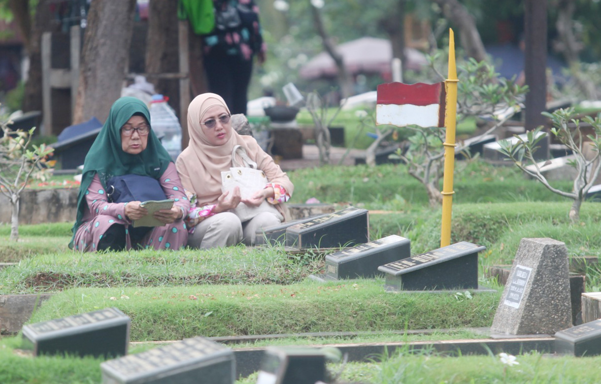 Sejumlah warga berdoa menaburkan bunga di makam keluarganya di tempat pemakaman umum Karet Bivak,Jakarta, Jumat(28/2/2025). (Beritanasional.com/Oke Atmaja)